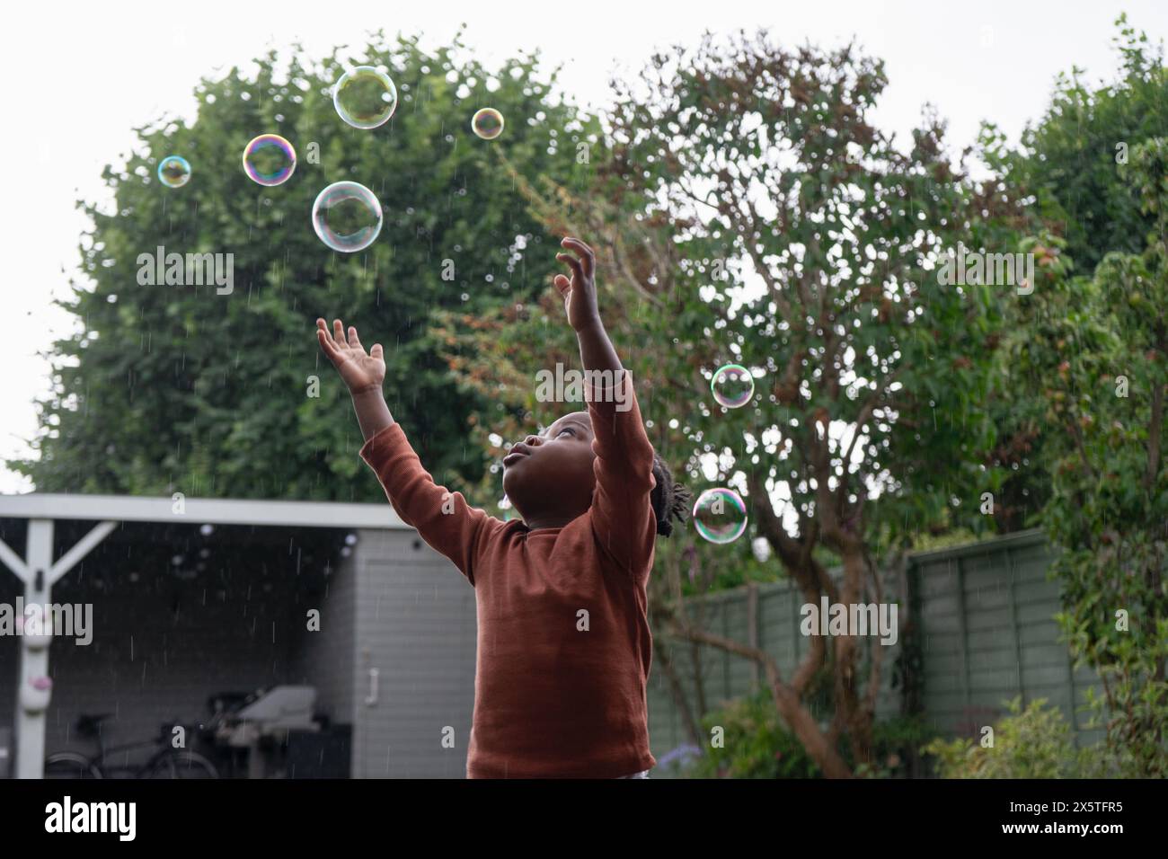 Ragazza (2-3) che gioca con le bolle di sapone Foto Stock
