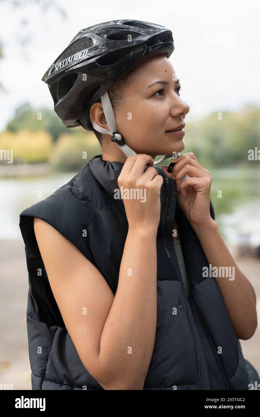 Donna che indossa il casco da bici nel parco Foto Stock