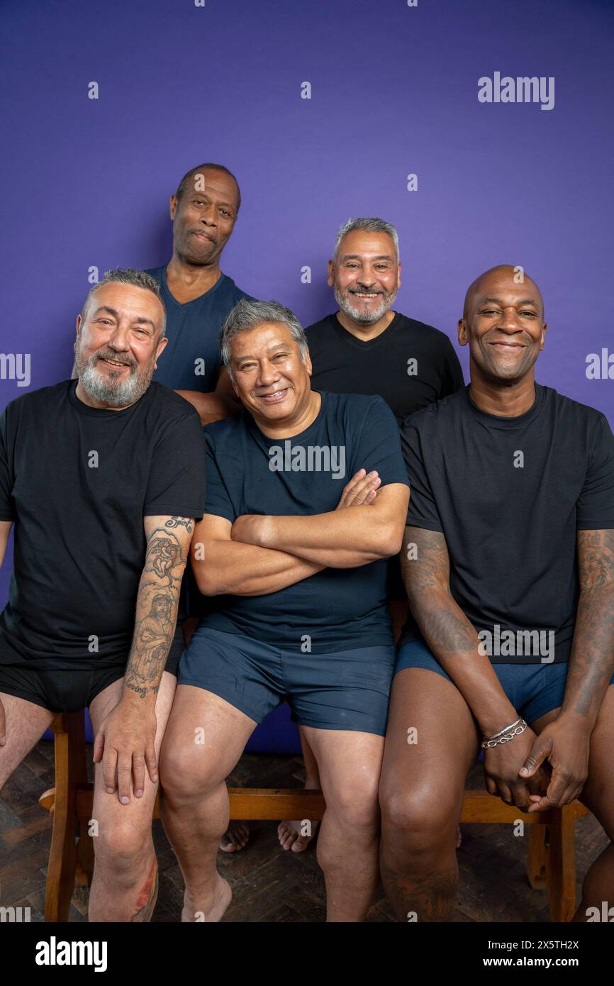 Ritratto di uomini sorridenti con t-shirt nere su sfondo viola Foto Stock