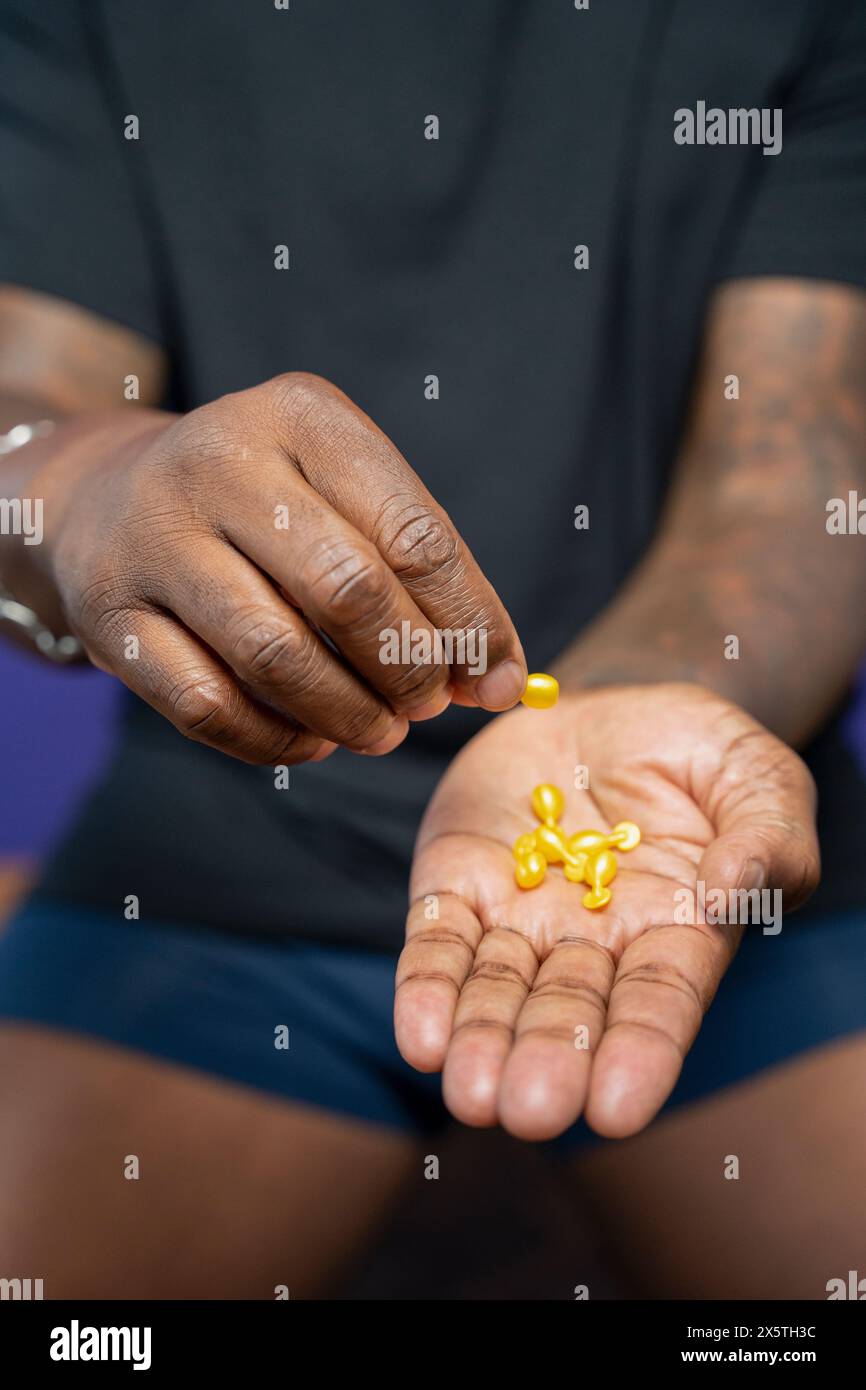 Primo piano di un uomo che tiene in mano le capsule gialle Foto Stock