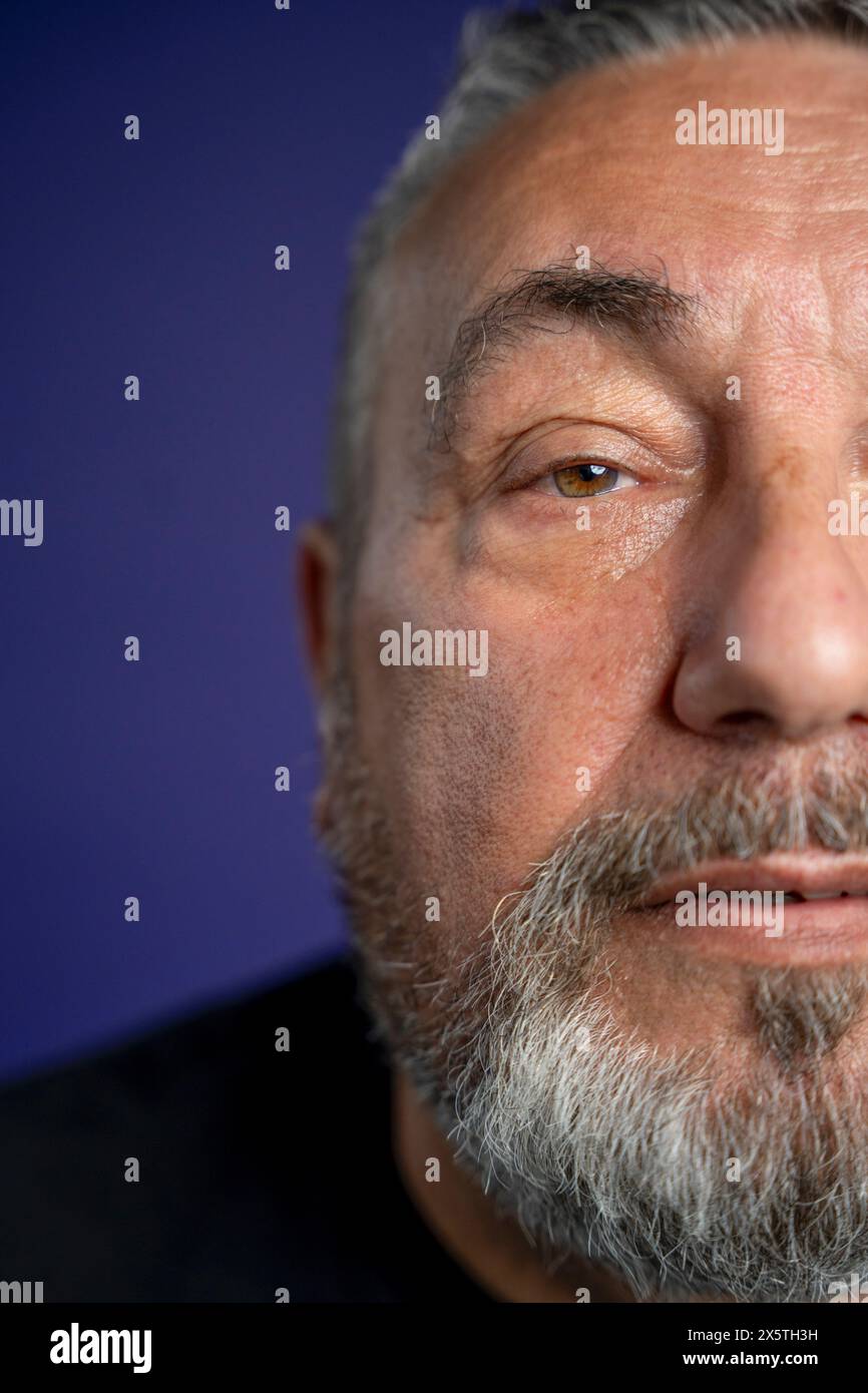 Ritratto di un uomo serio con barba su sfondo viola Foto Stock