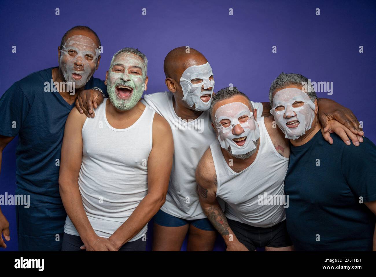 Ritratto di uomini con maschere facciali su sfondo viola Foto Stock