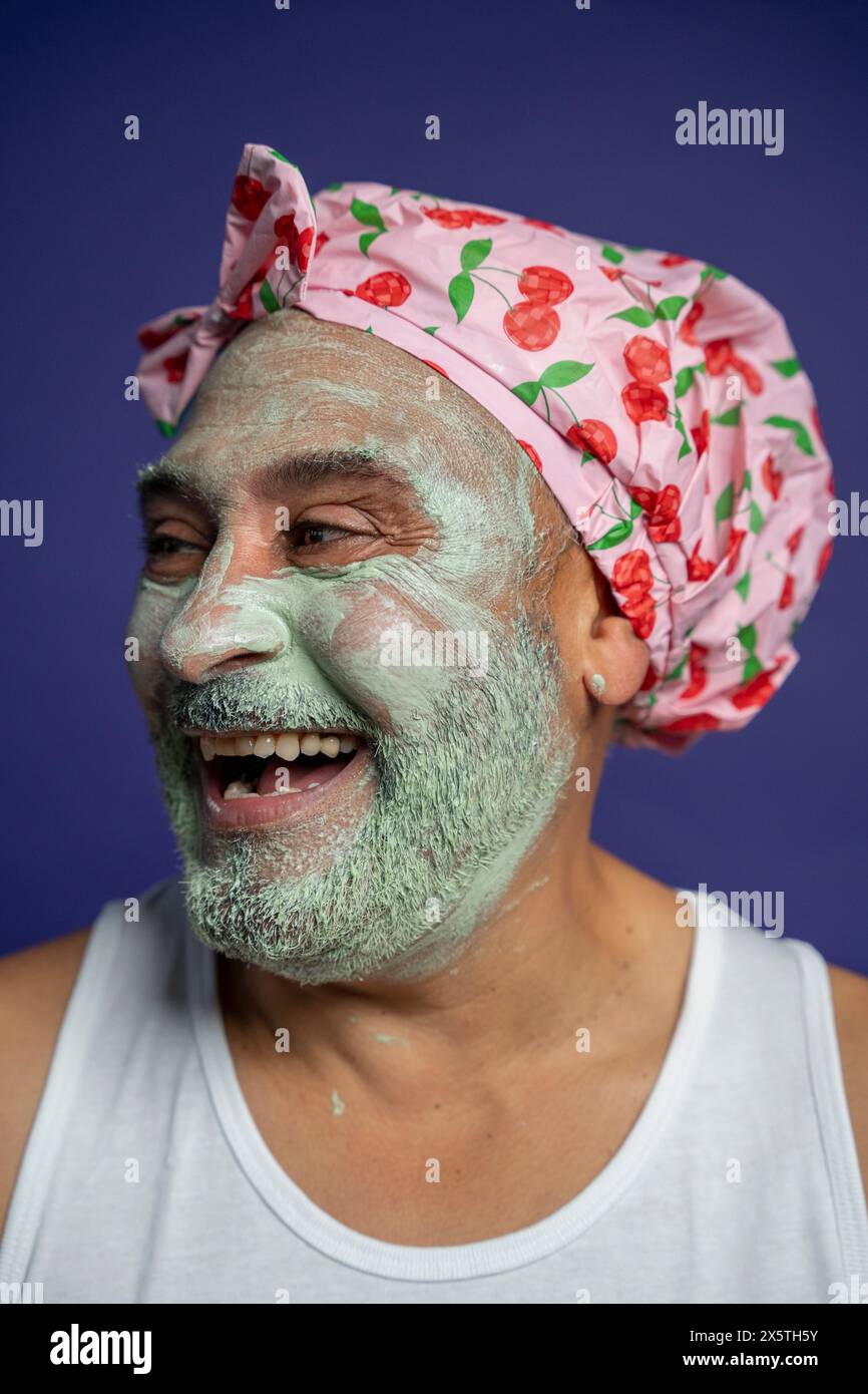 Ritratto dell'uomo con maschera facciale e cappellino su sfondo viola Foto Stock