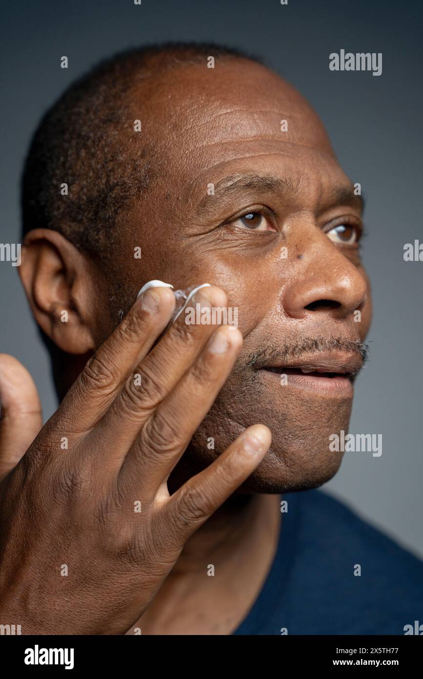 Ritratto dell'uomo che applica la crema sul viso Foto Stock
