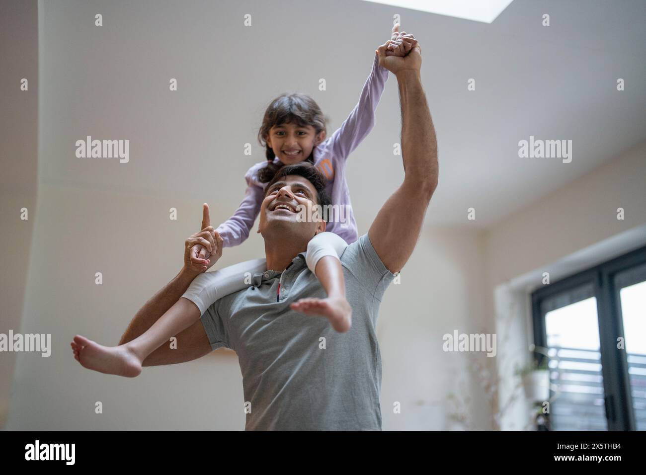 Padre che porta la figlia sulle spalle a casa Foto Stock