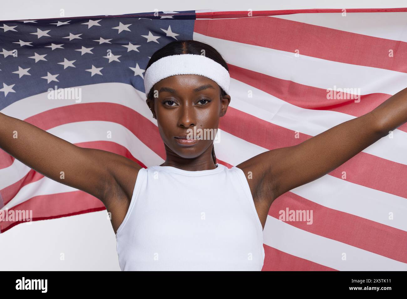 Ritratto in studio di una donna atletica in abbigliamento sportivo con bandiera americana Foto Stock