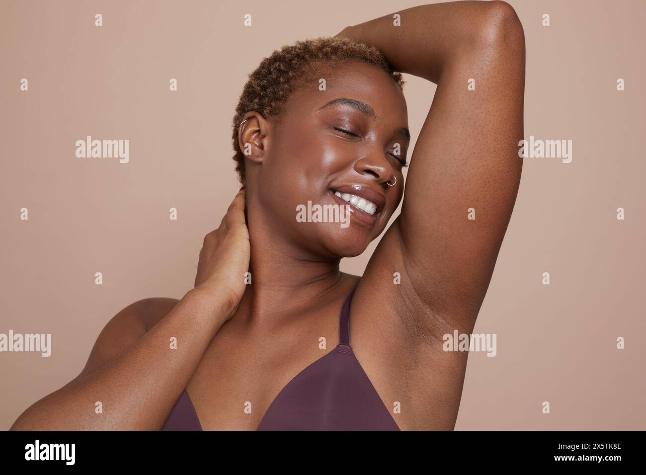 Ritratto in studio di una donna sorridente con le braccia alzate e gli occhi chiusi Foto Stock