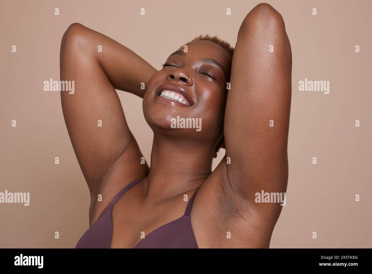 Ritratto in studio di una donna sorridente con le braccia alzate e gli occhi chiusi Foto Stock