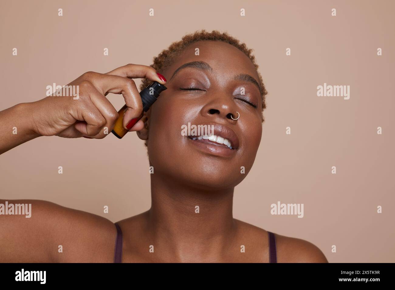 Ritratto in studio di una donna che applica siero sul viso Foto Stock