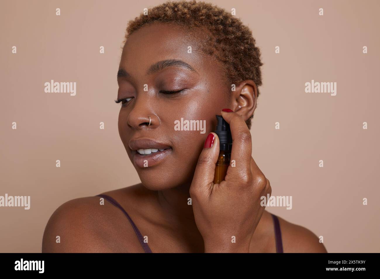 Ritratto in studio di una donna che applica siero sul viso Foto Stock