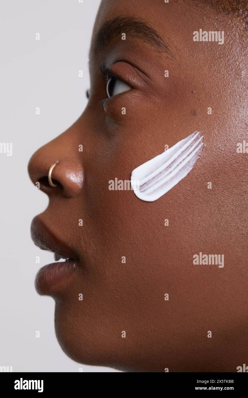 Profilo di donna con crema per il viso sulla guancia Foto Stock