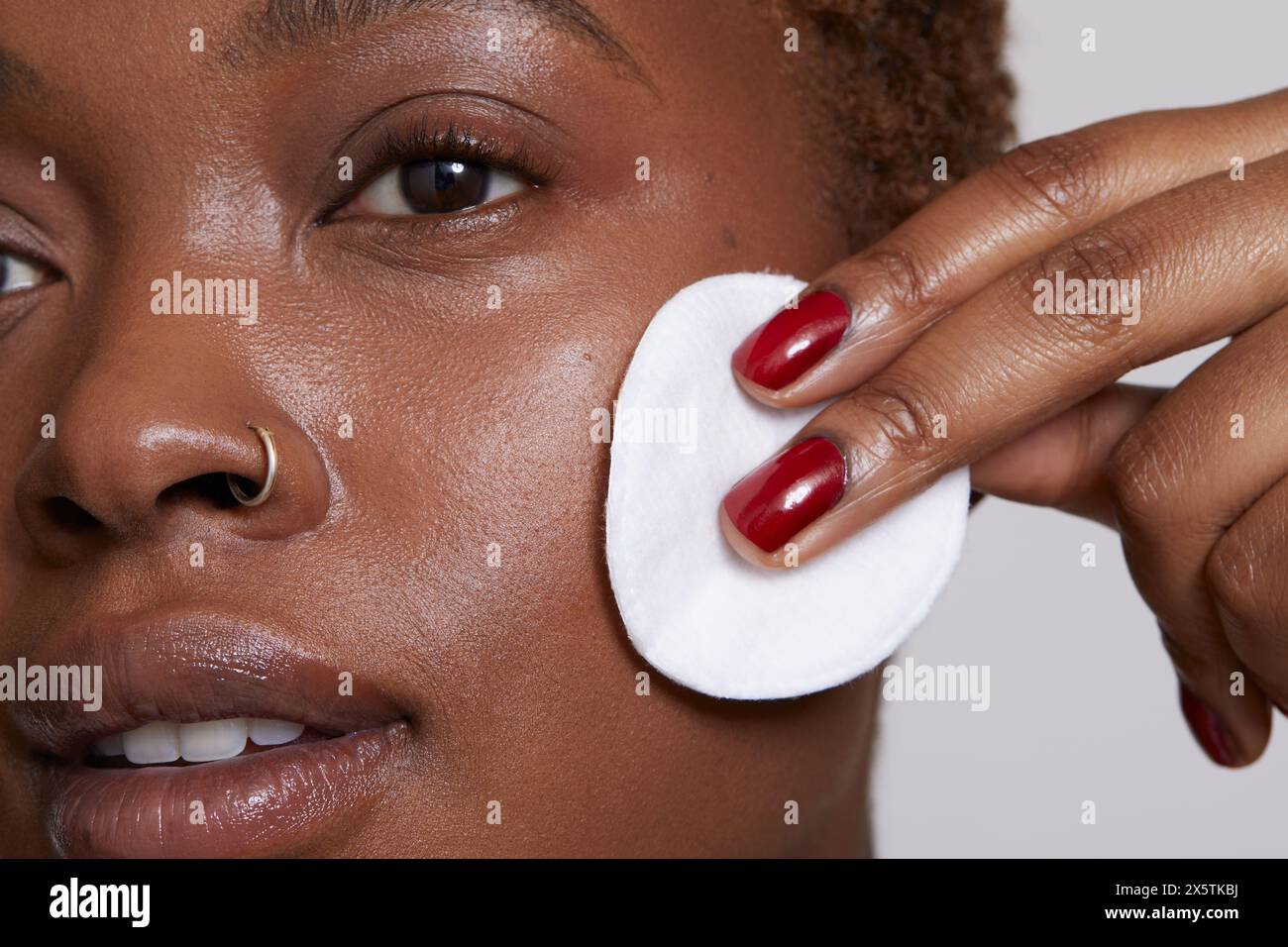 Primo piano di una donna che pulisce il viso con un panno di cotone Foto Stock