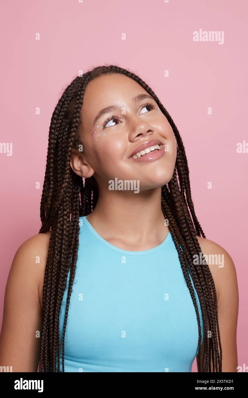 Ritratto in studio di una ragazza sorridente con trecce e adesivi decorativi sul viso Foto Stock