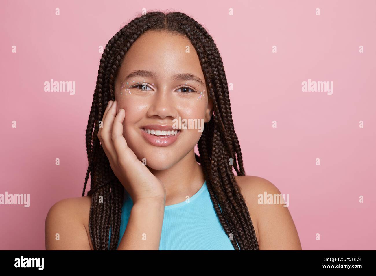Ritratto in studio di una ragazza sorridente con trecce e adesivi decorativi sul viso Foto Stock