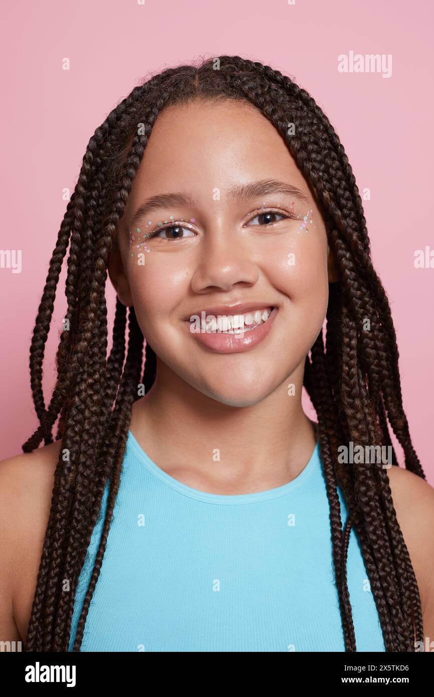 Ritratto in studio di una ragazza sorridente con trecce e adesivi decorativi sul viso Foto Stock