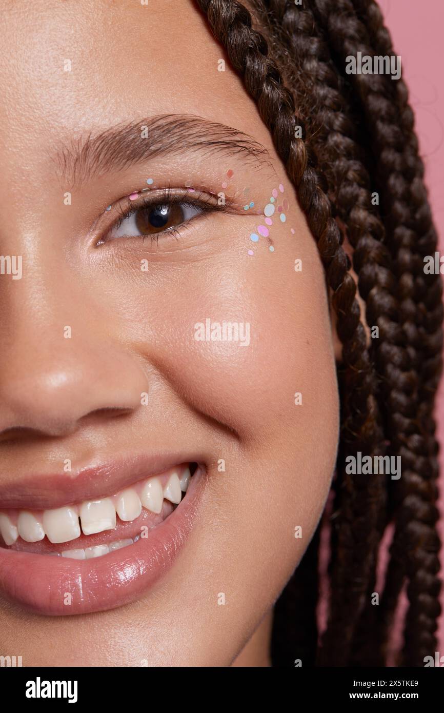 Primo piano di una ragazza sorridente con adesivi decorativi sul viso Foto Stock