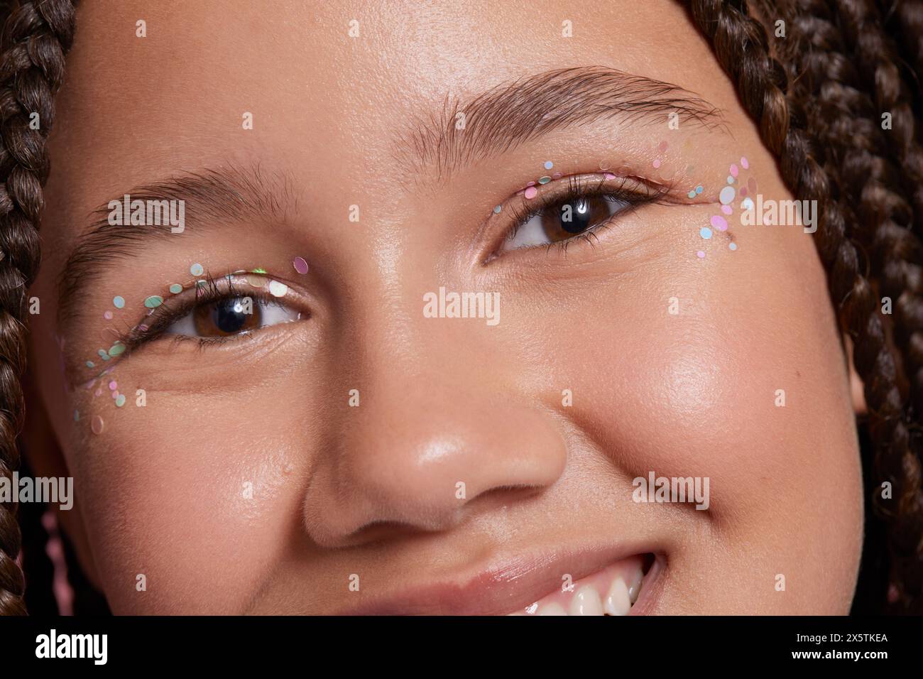 Primo piano di una ragazza sorridente con adesivi decorativi sul viso Foto Stock