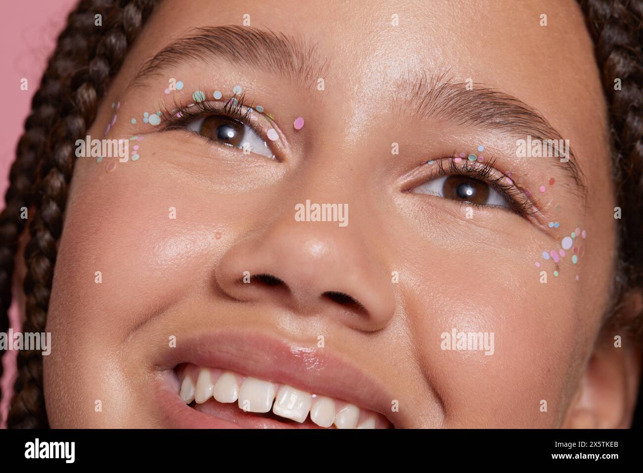 Primo piano di una ragazza sorridente con adesivi decorativi sul viso Foto Stock