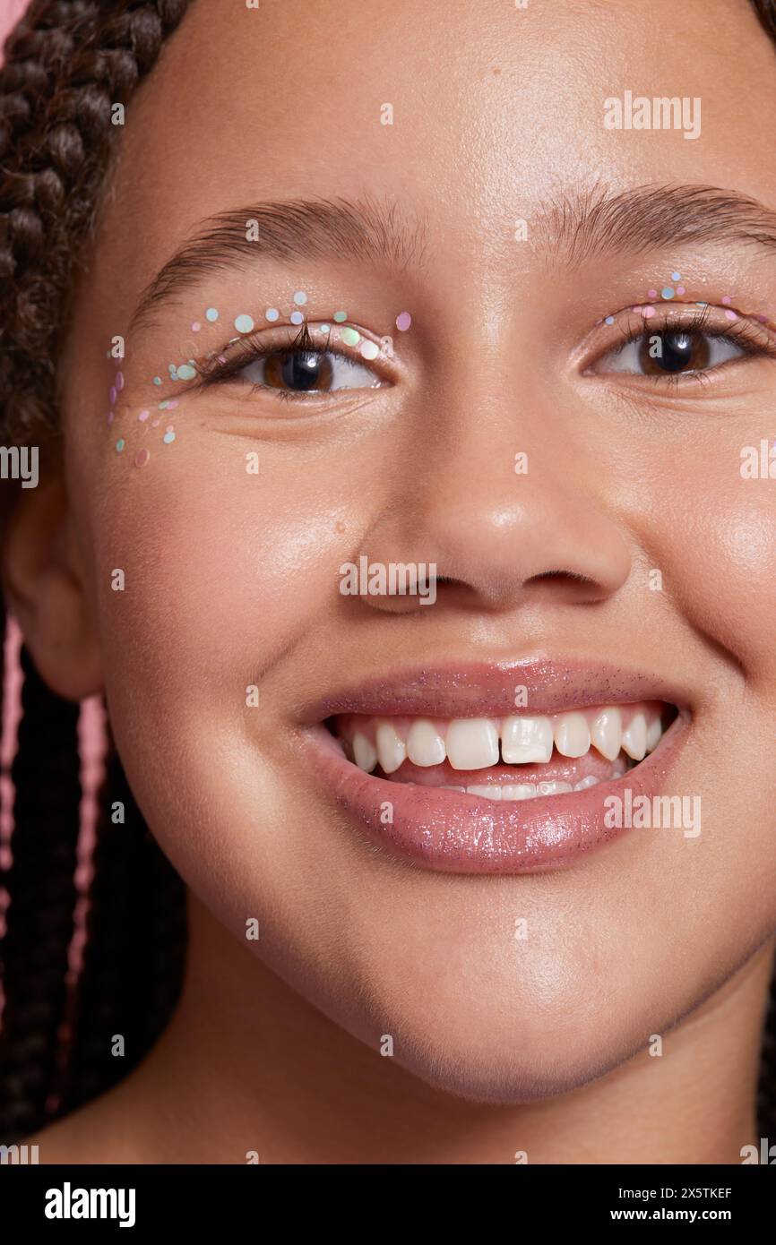 Primo piano di una ragazza sorridente con adesivi decorativi sul viso Foto Stock