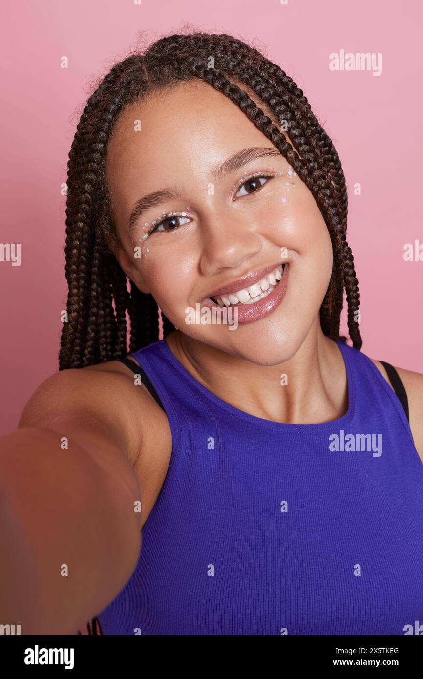 Ritratto di una ragazza sorridente con trecce e adesivi decorativi sul viso Foto Stock
