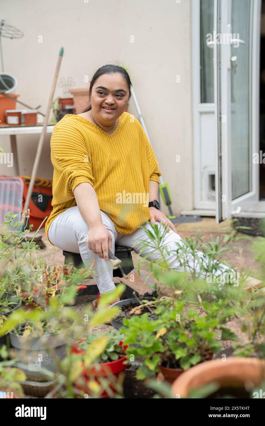 Giovane donna con sindrome di Down che piantano fiori in giardino Foto Stock