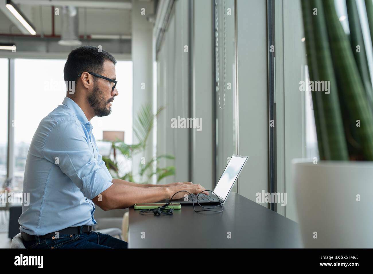 Uomo d'affari con un computer portatile che lavora in un ufficio moderno Foto Stock
