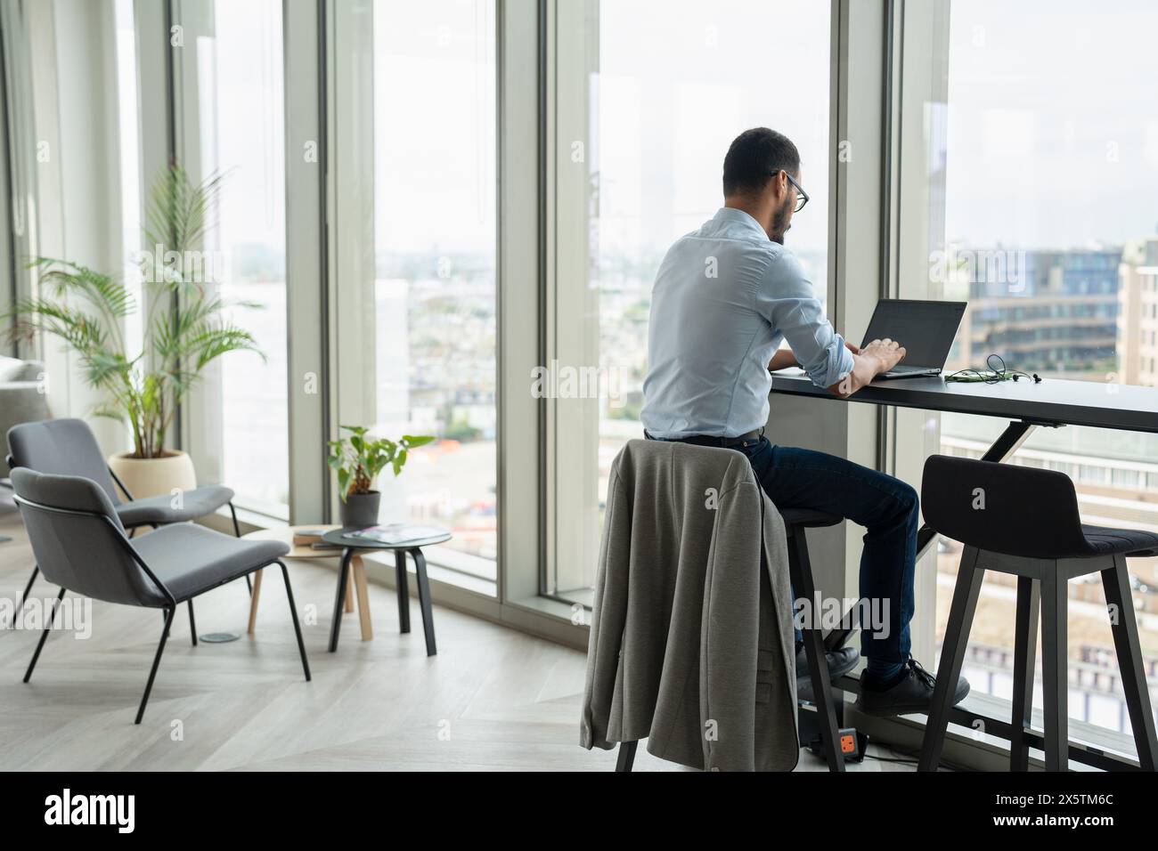 Uomo d'affari con un computer portatile che lavora in un ufficio moderno Foto Stock