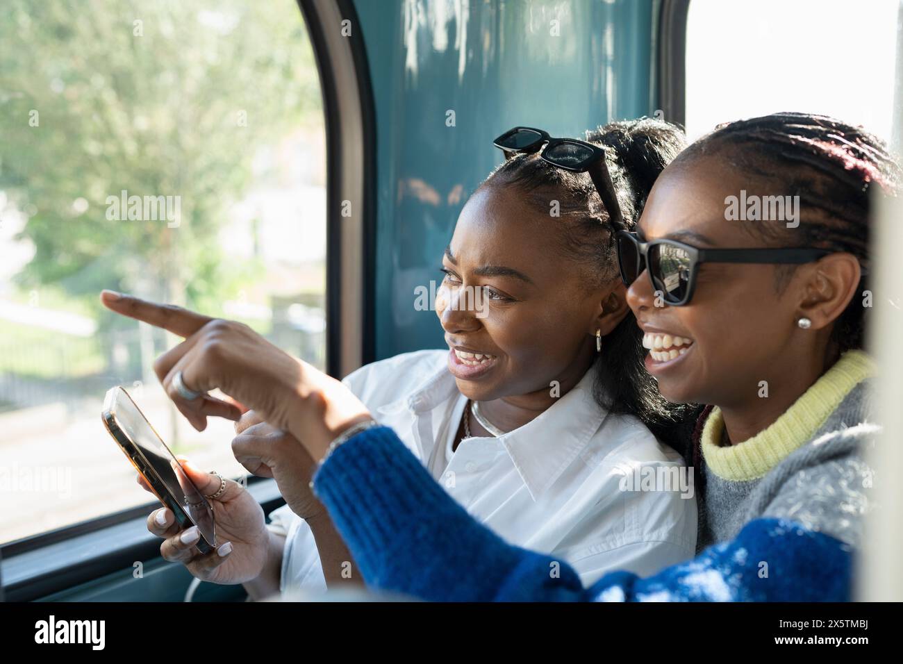 Giovani amiche che viaggiano in autobus cittadino e usano il telefono Foto Stock