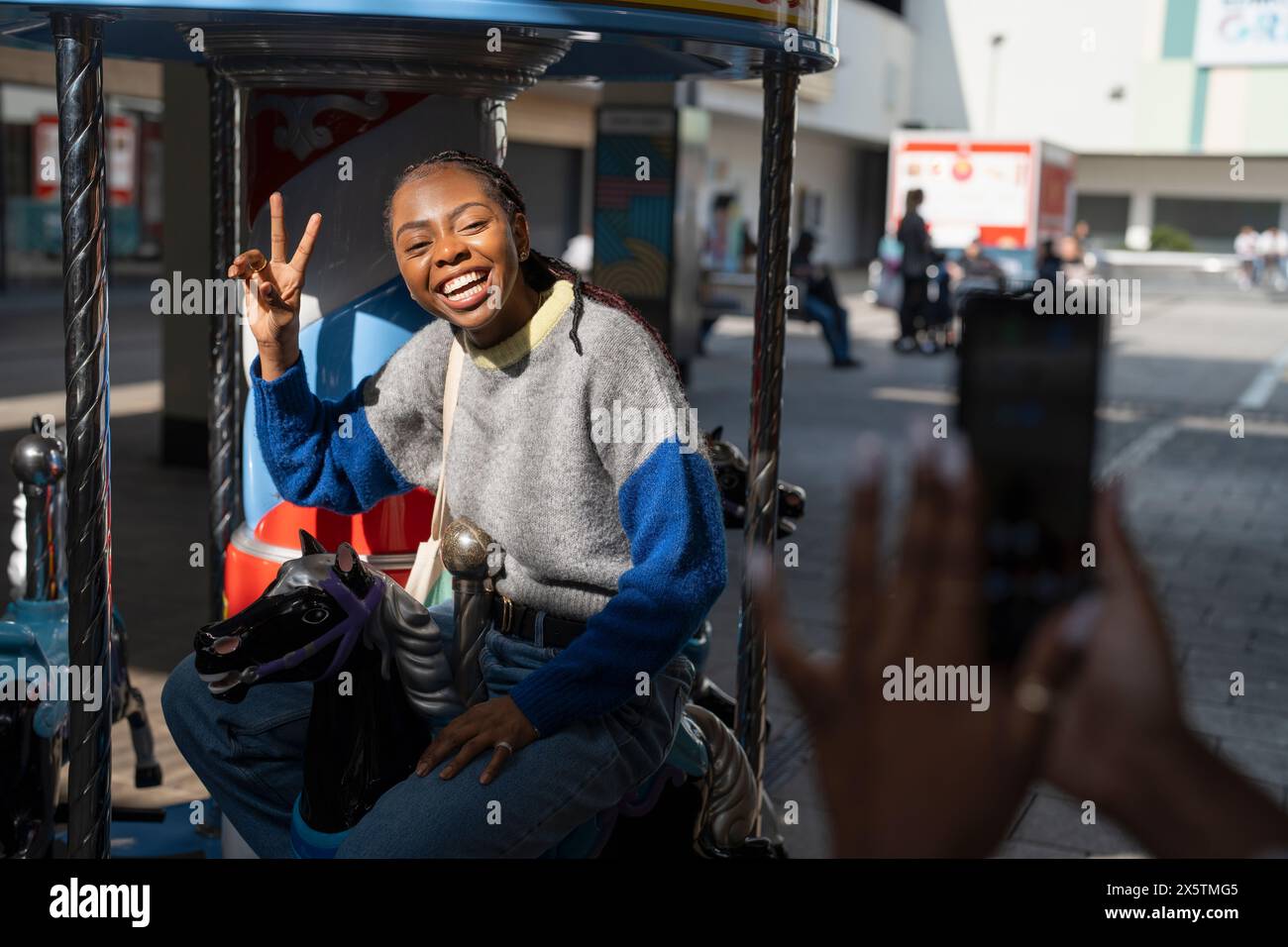 Una giovane donna sorridente che posa per una foto durante il giro in giostra Foto Stock