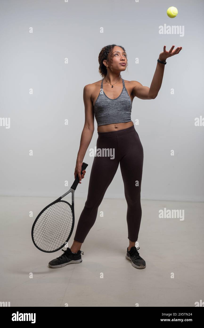 Donna che tiene la racchetta da tennis e lancia la palla da tennis Foto Stock