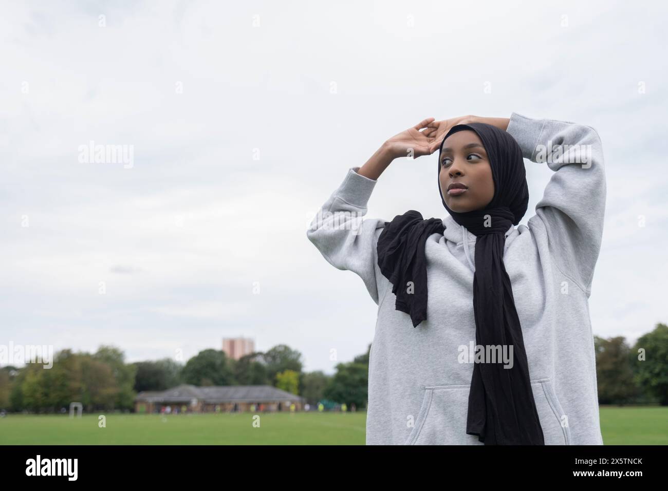 Ritratto di donna in hijab in piedi in un campo di calcio con le braccia sollevate Foto Stock