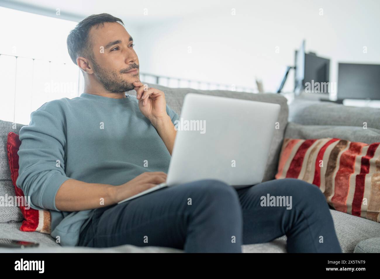 Uomo maturo che lavora su un laptop sul divano di casa Foto Stock