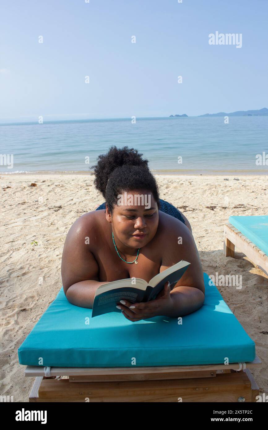 Giovane donna che si rilassa e legge sulla spiaggia Foto Stock