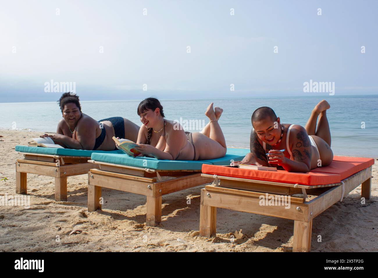 Gruppo di donne che si rilassano e leggono sulla spiaggia Foto Stock