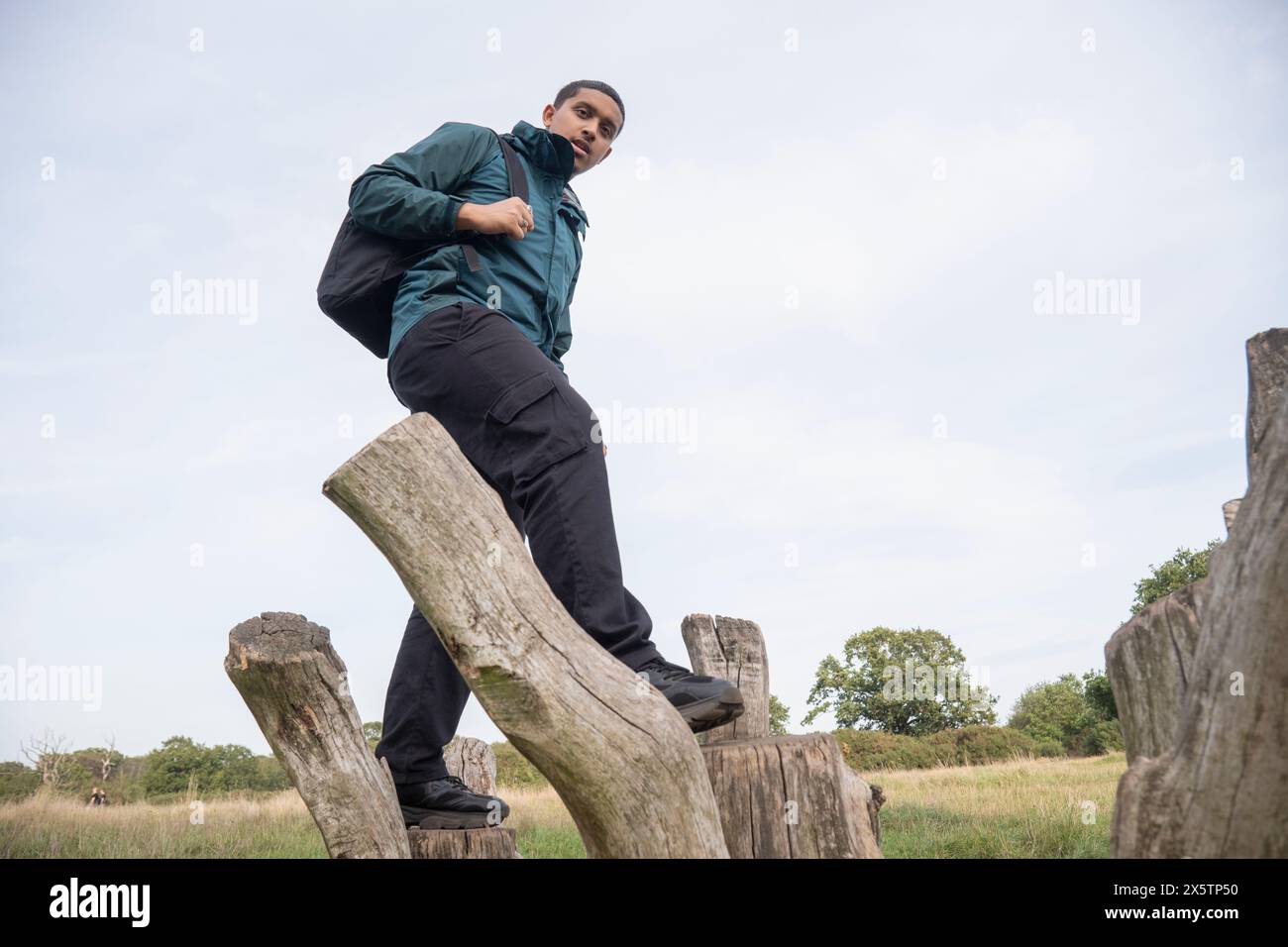 Ritratto dell'uomo con zaino che cammina su vecchi pali di legno Foto Stock