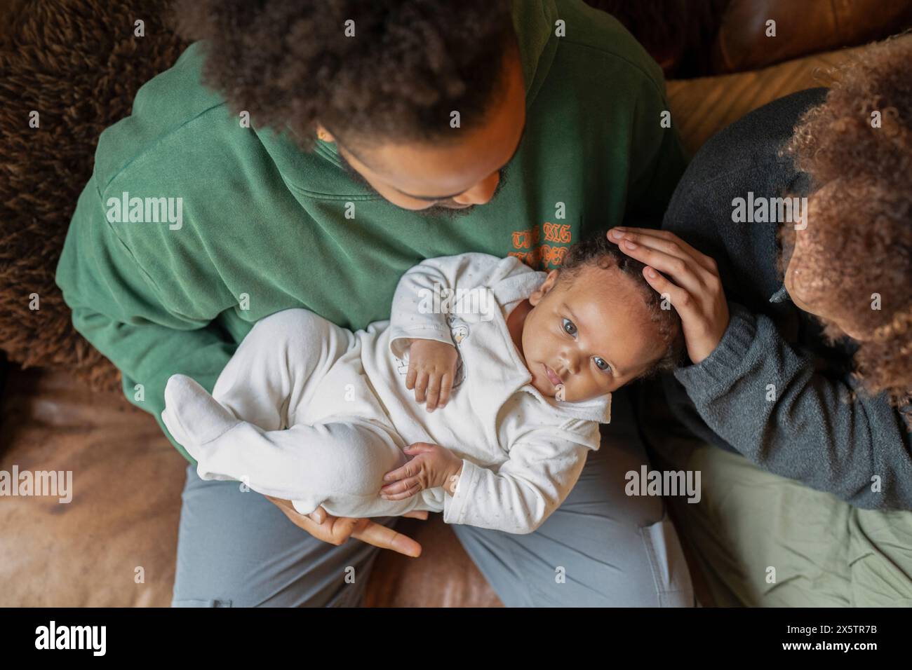 Padre che tiene in braccio una figlia, madre che tocca la testa dei bambini Foto Stock