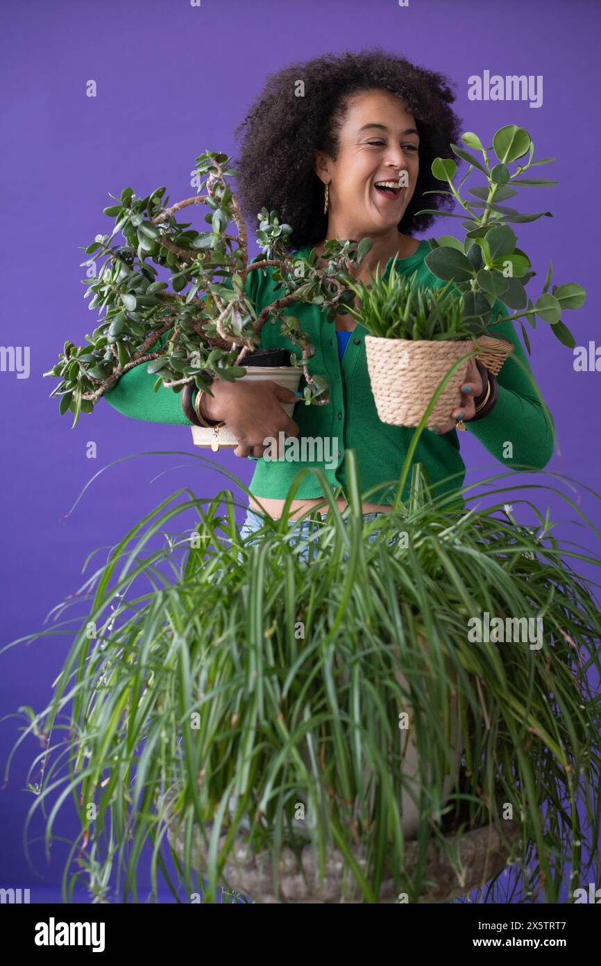 Ritratto in studio di una donna sorridente che tiene le piante in vaso Foto Stock