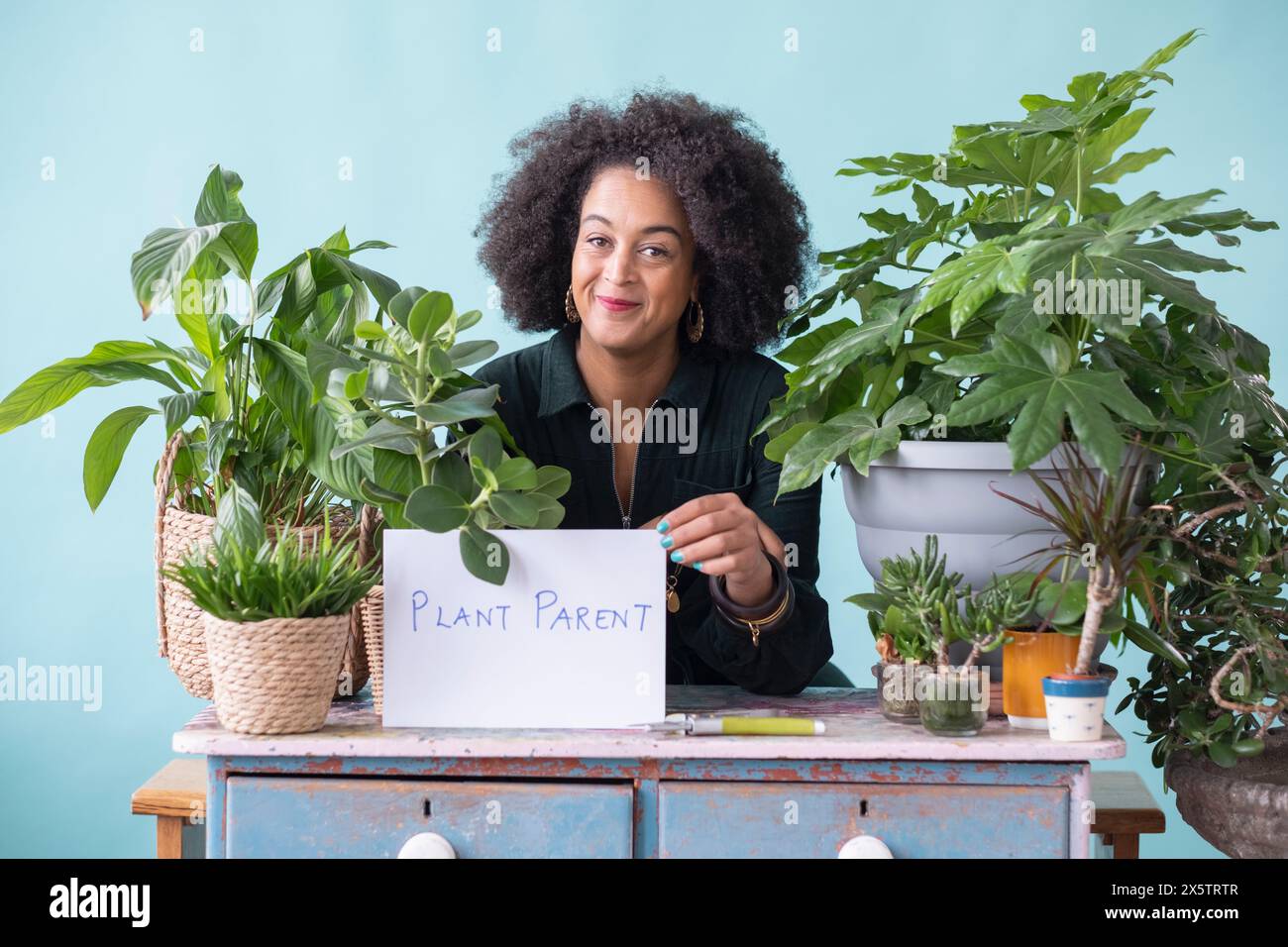 Ritratto in studio di una donna sorridente con piante in vaso e segno Foto Stock