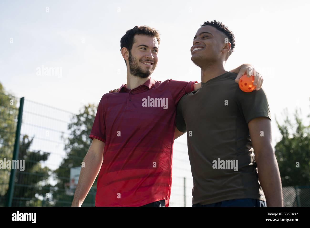 Uomini sorridenti in piedi nel campo da pallacanestro Foto Stock