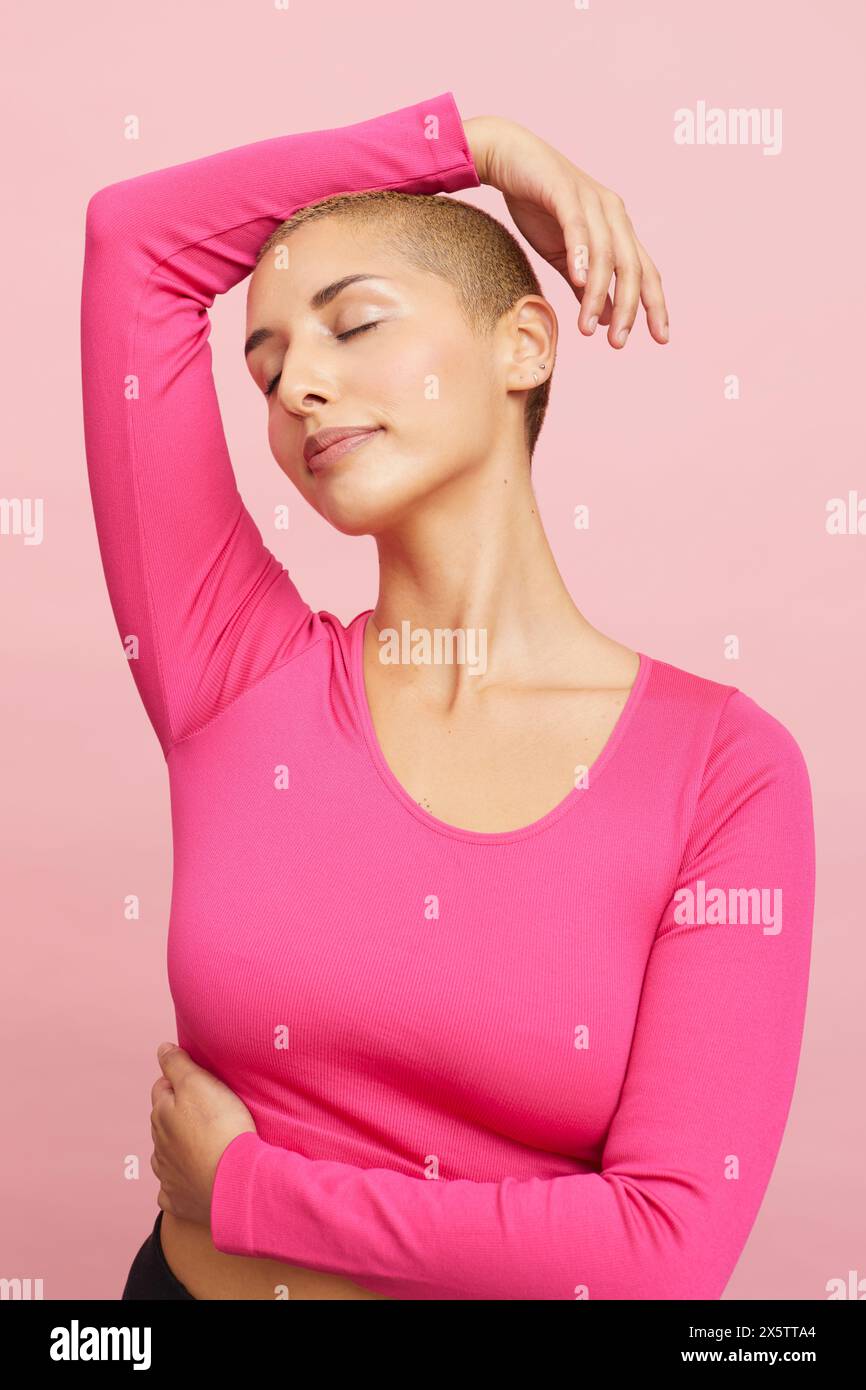 Donna con capelli biondi corti, occhi chiusi e braccio sollevato Foto Stock