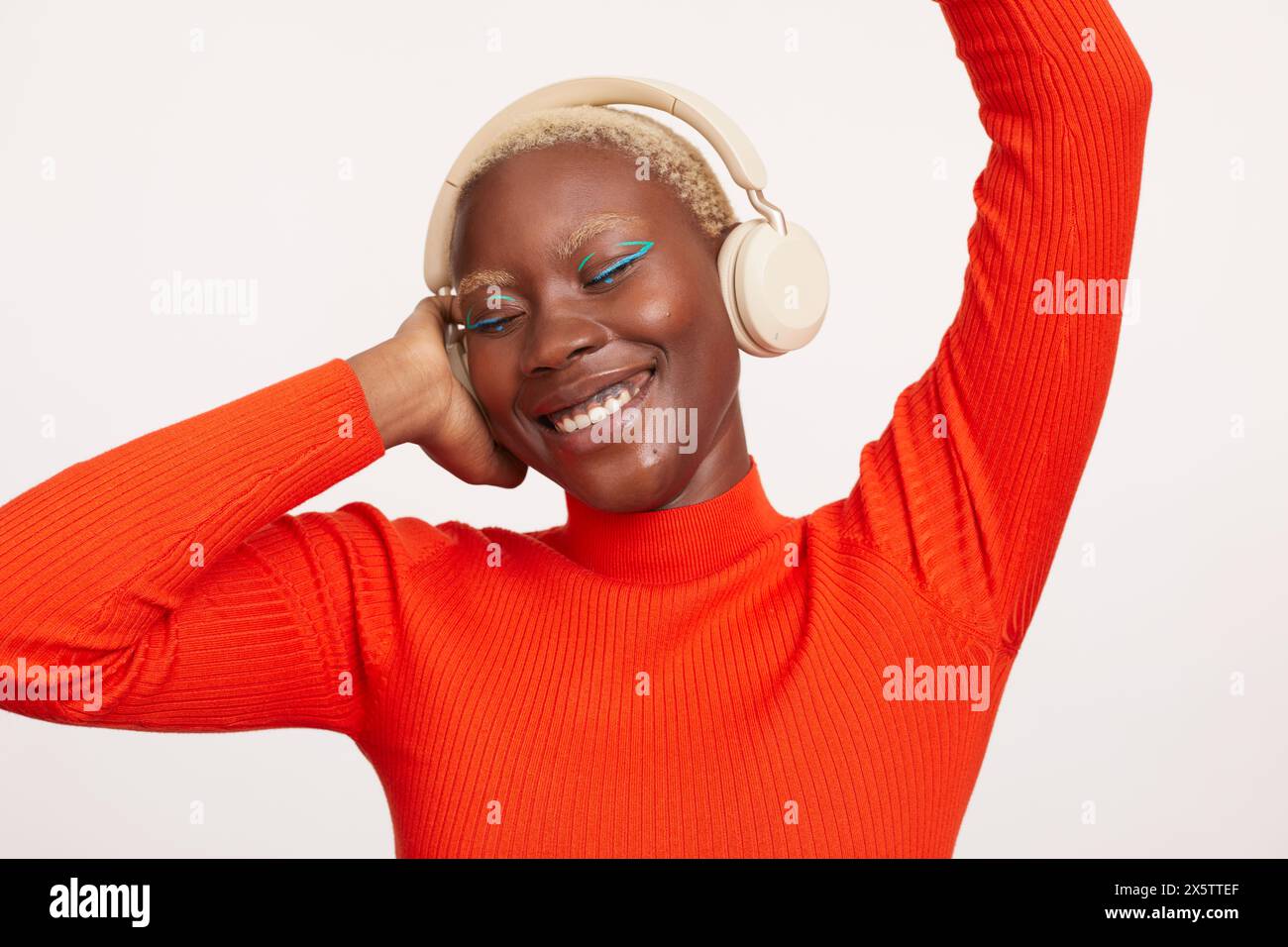 Donna sorridente con capelli bianchi corti, che ascolta musica Foto Stock