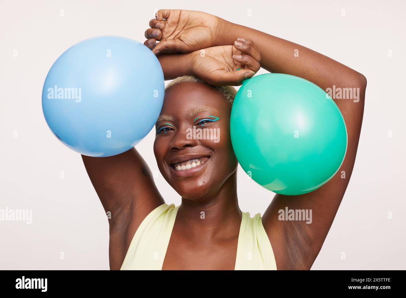 Donna sorridente con i capelli bianchi corti, che regge palloncini Foto Stock