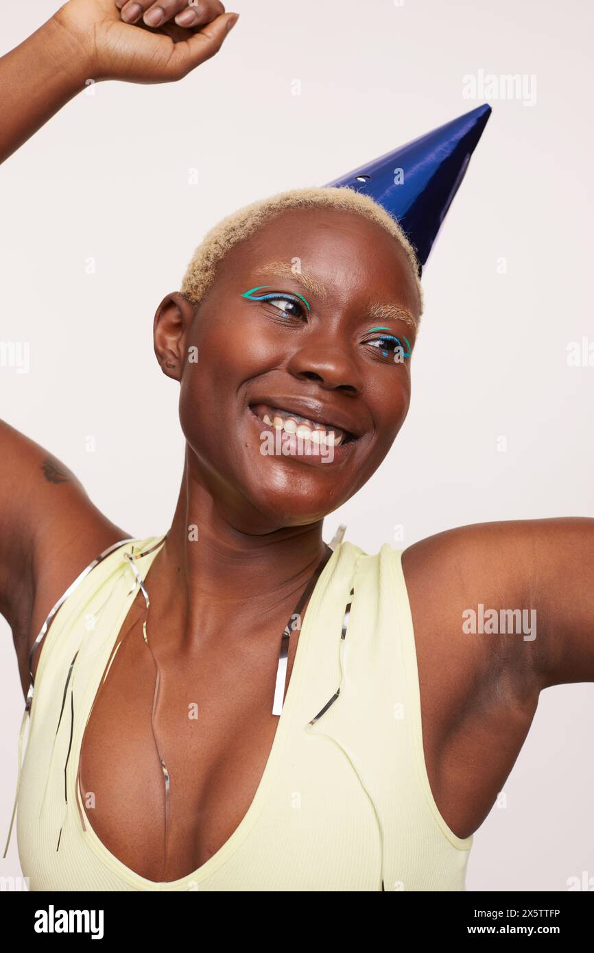 Donna sorridente con capelli bianchi corti, con cappello blu da festa Foto Stock