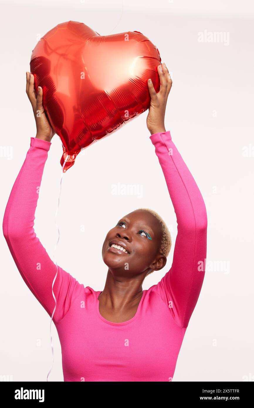 Donna con capelli bianchi corti, che tiene il palloncino a forma di cuore Foto Stock
