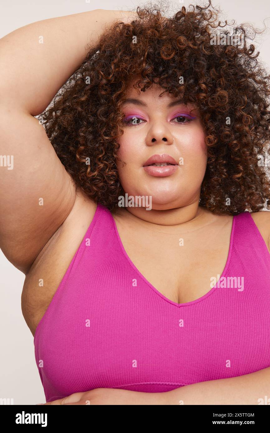 Bruna donna che indossa un reggiseno rosa, guarda la macchina fotografica Foto Stock
