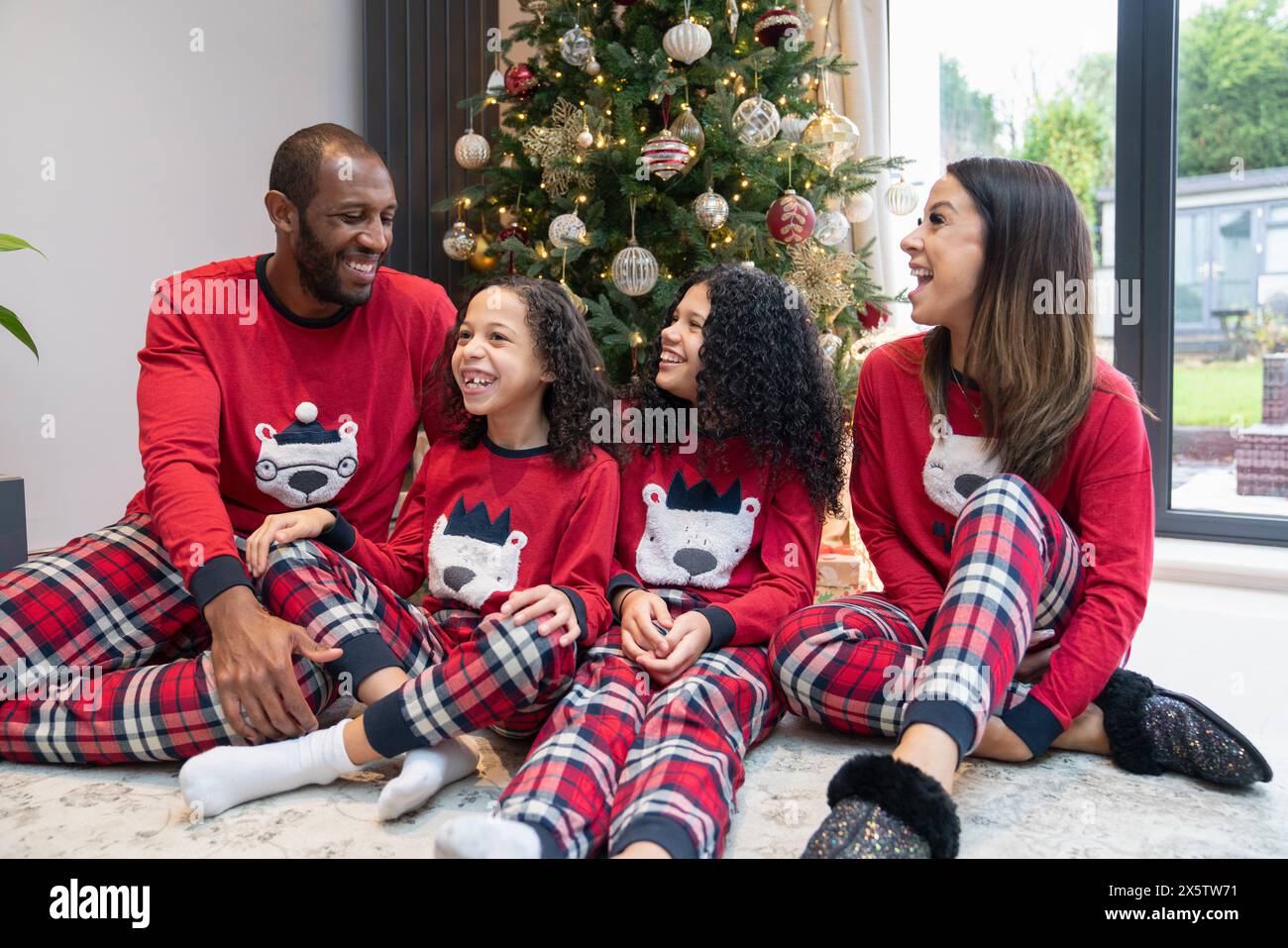 Ritratto di genitori sorridenti con due figlie davanti all'albero di Natale Foto Stock