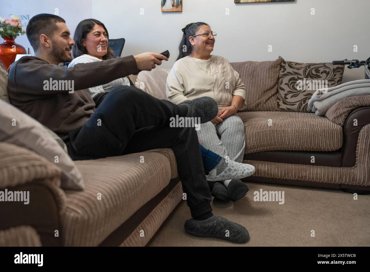 Sorridente famiglia di tre generazioni che guarda la TV Foto Stock