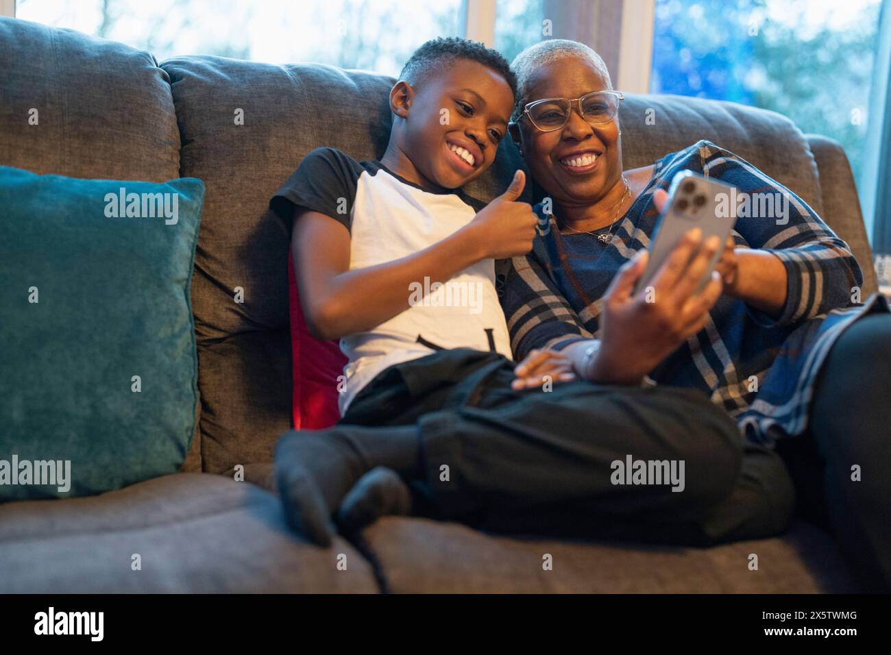 Nonna e nipote con smartphone seduti sul divano Foto Stock