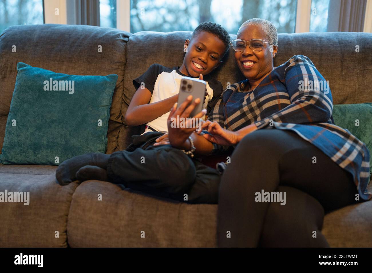 Nonna e nipote con smartphone seduti sul divano Foto Stock