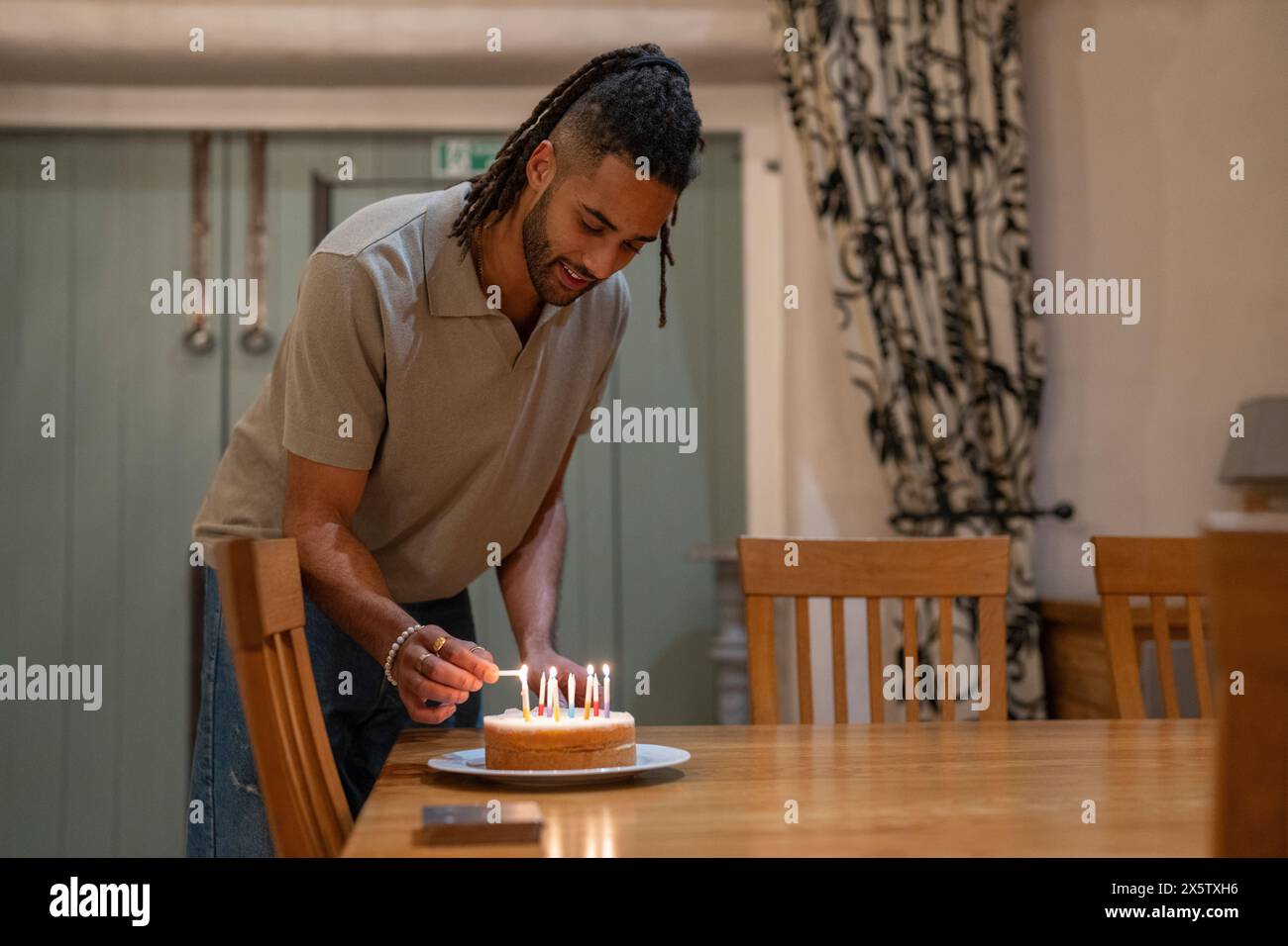 Uomo che accende le candele sulla torta di compleanno Foto Stock